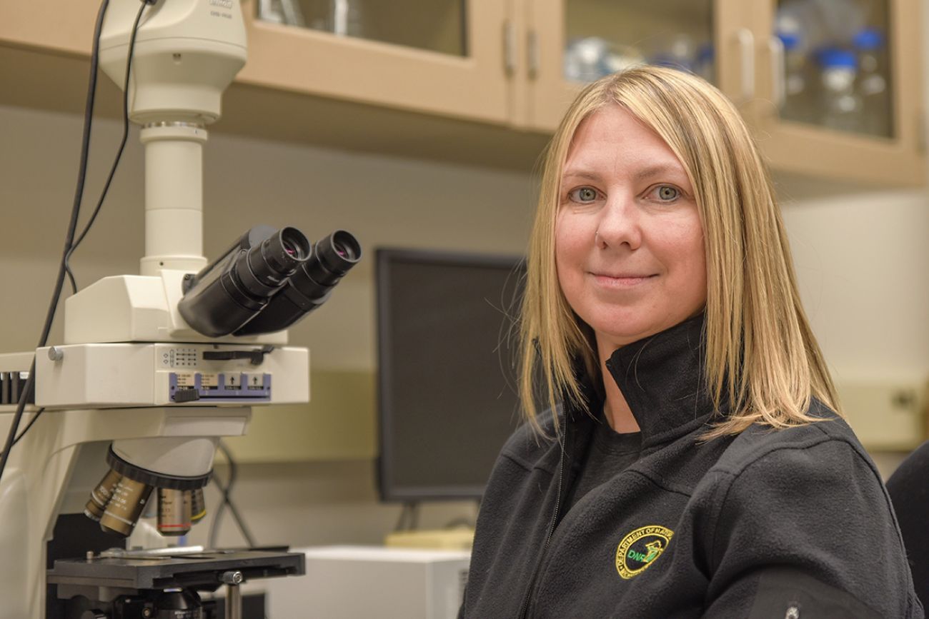 a woman sitting next to microscope