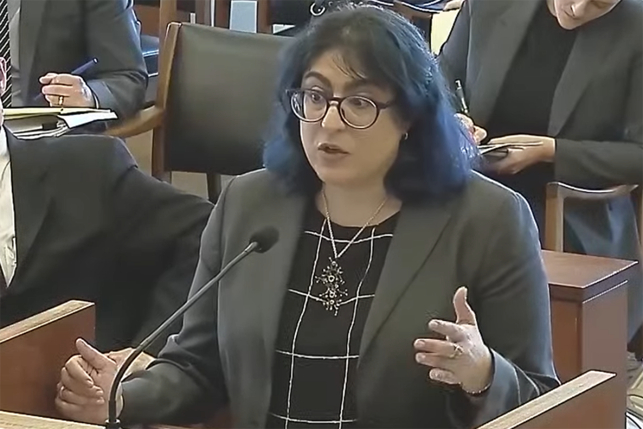 Woman, wearing a black top, speaks into a small microphone