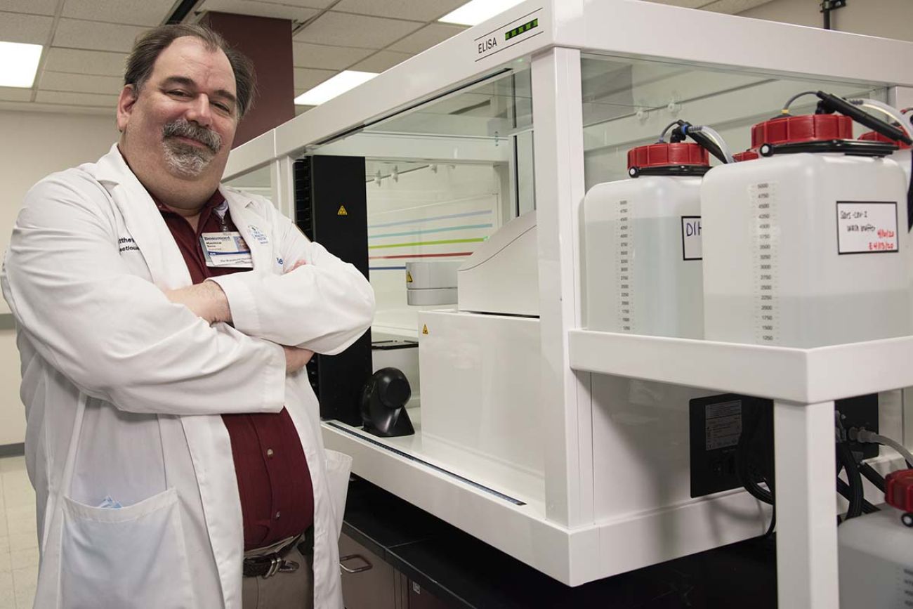 Dr. Matthew Sims is posing for a picture next to some lab equipment