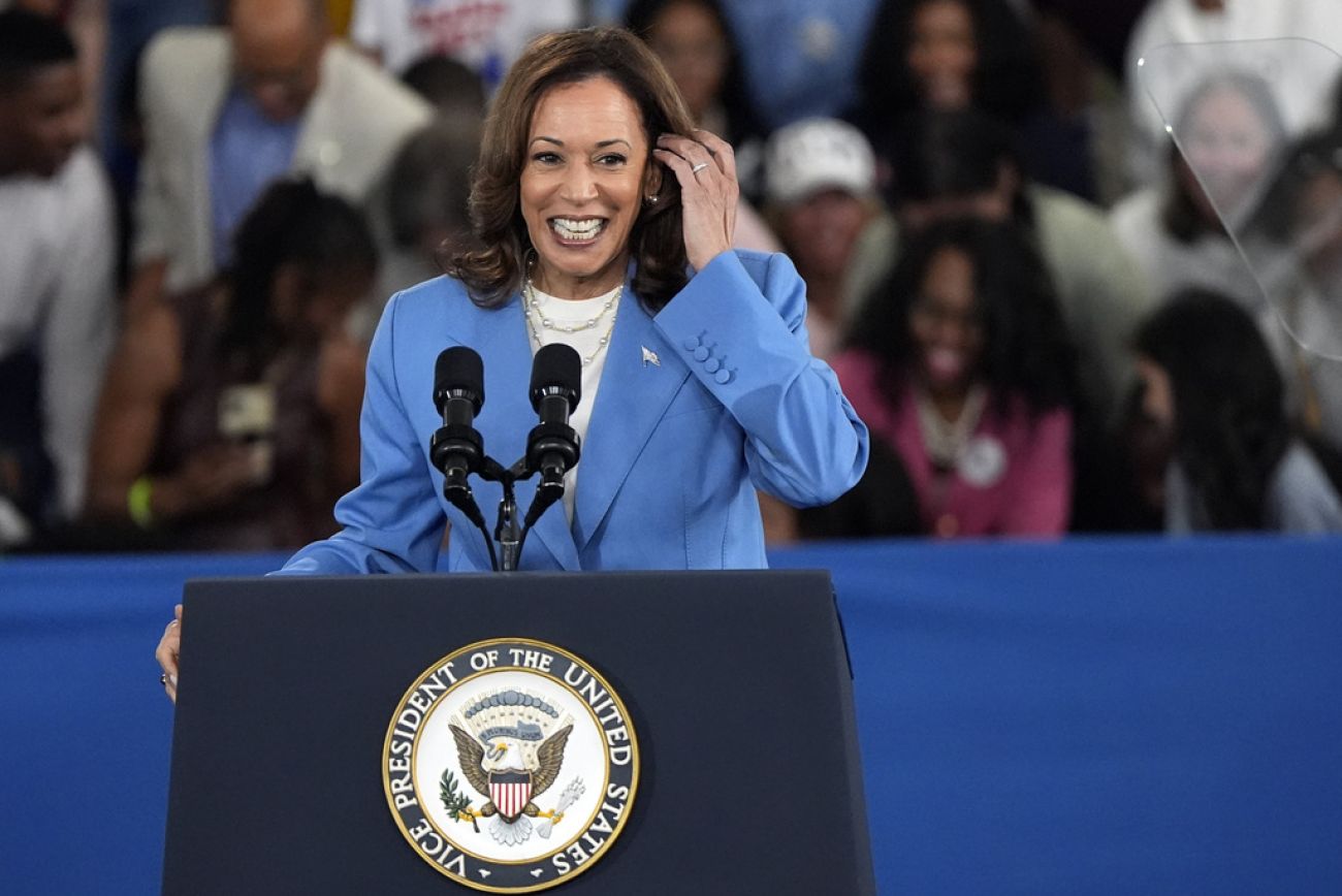 Vice President Kamala Harris, wearing a light blue jacket, speaking into a microphone