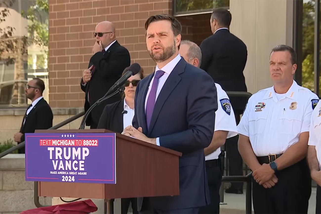 JD Vance standing at a podium outside of the Shelby Township Police Departmen