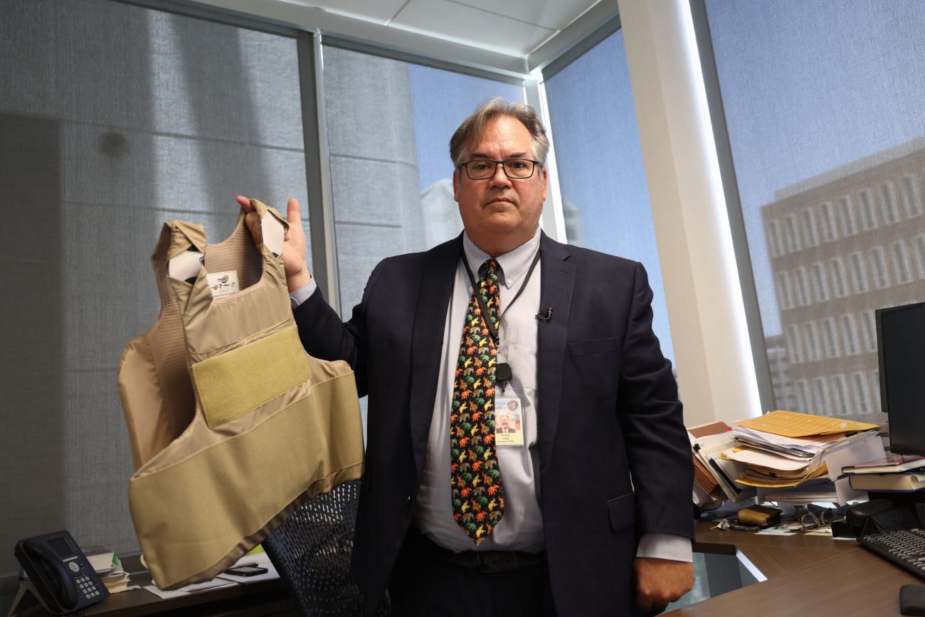 Tom Liddy holding up a bulletproof vest