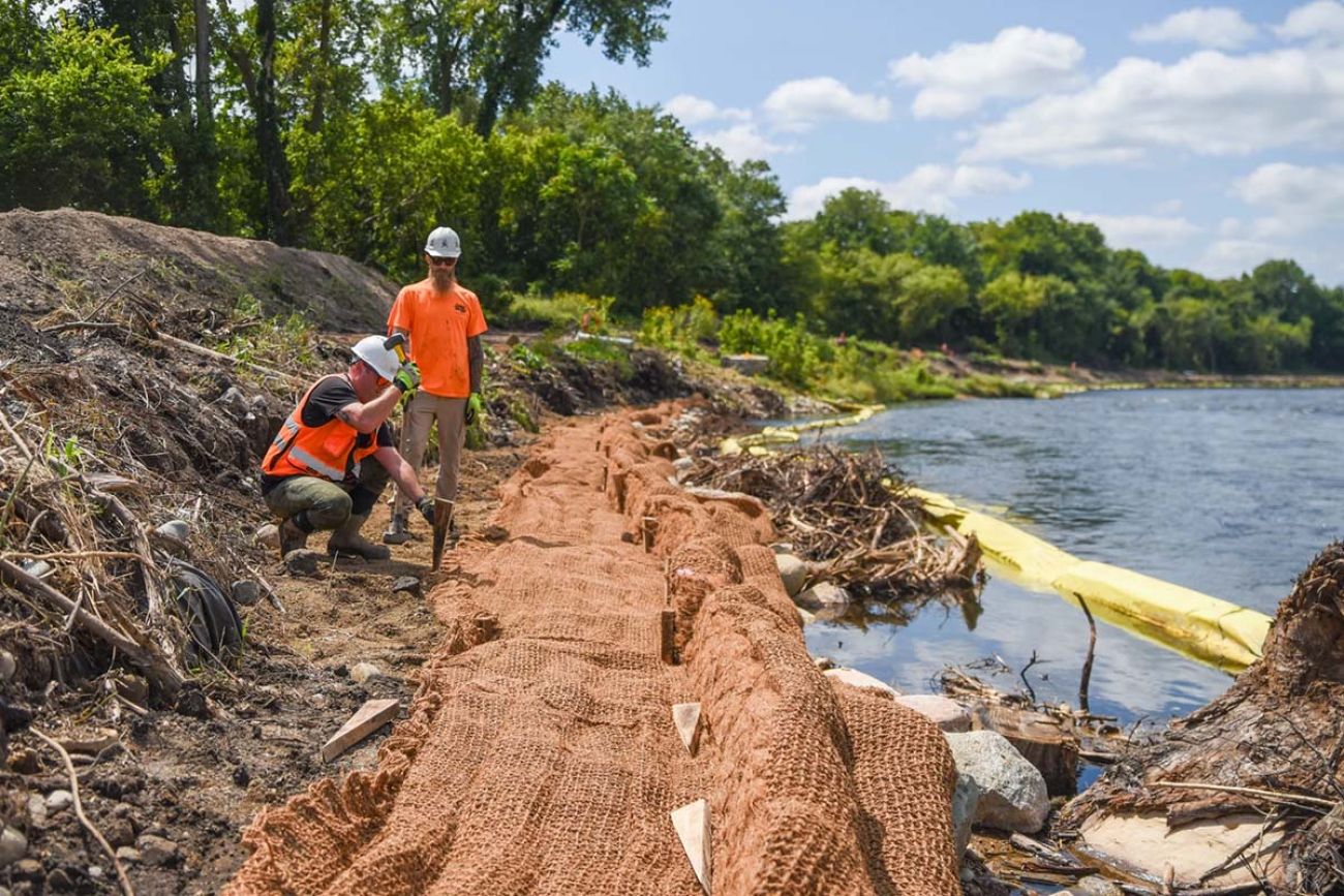 Ryan Allison, ecologist with SWCA Environmental Consultants, pounds in a stake to hold netting as Thomas Webster looks on.