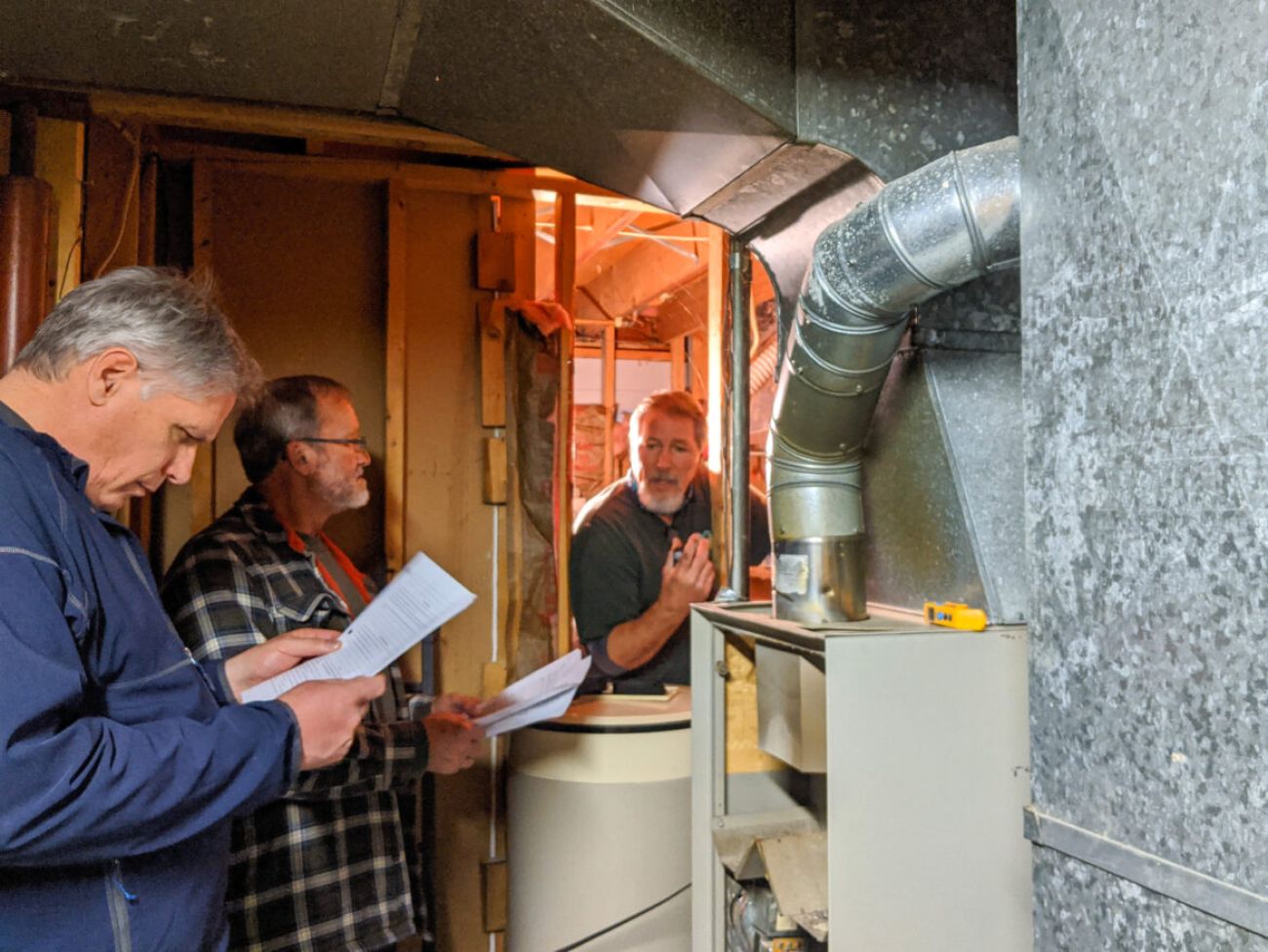 Three men look at a furnace