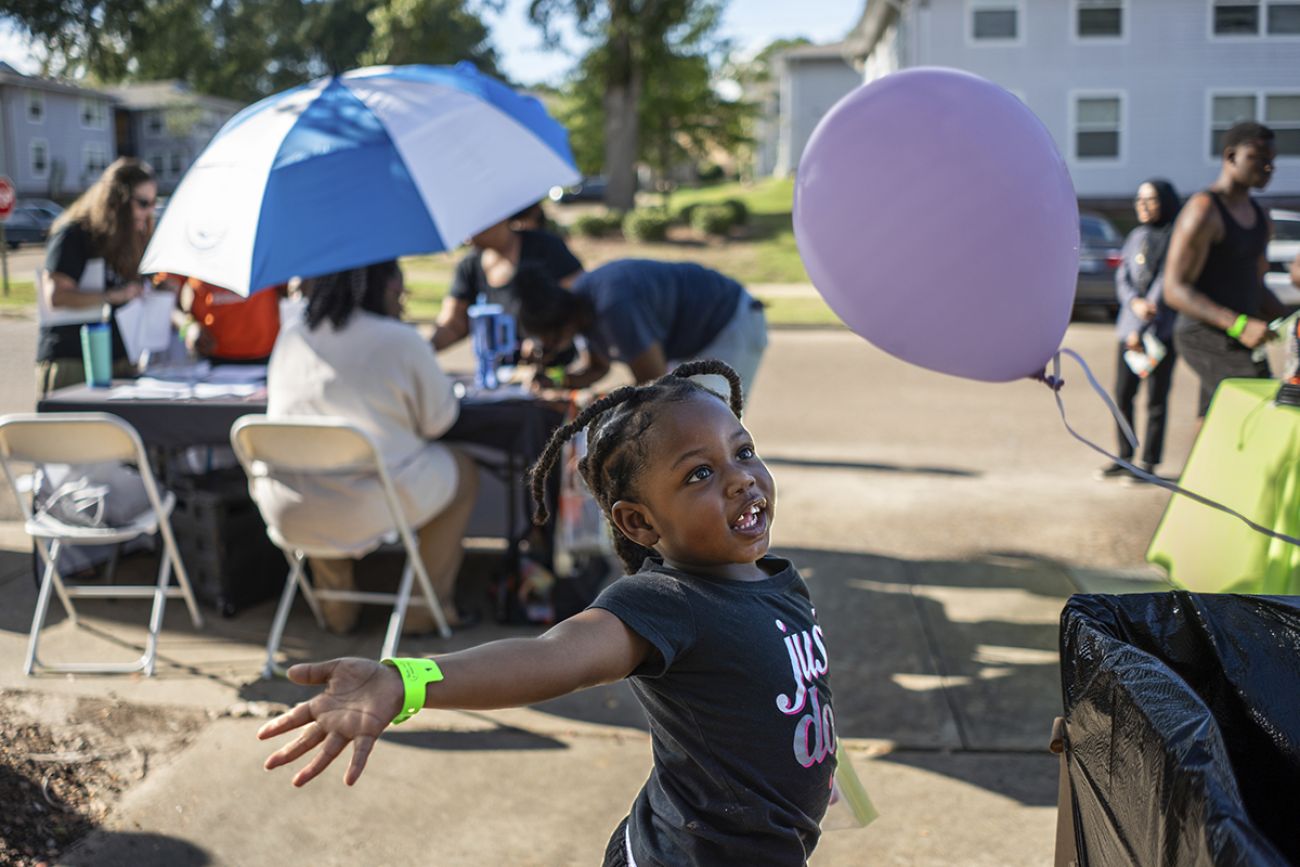A girl next to a lavender ballon