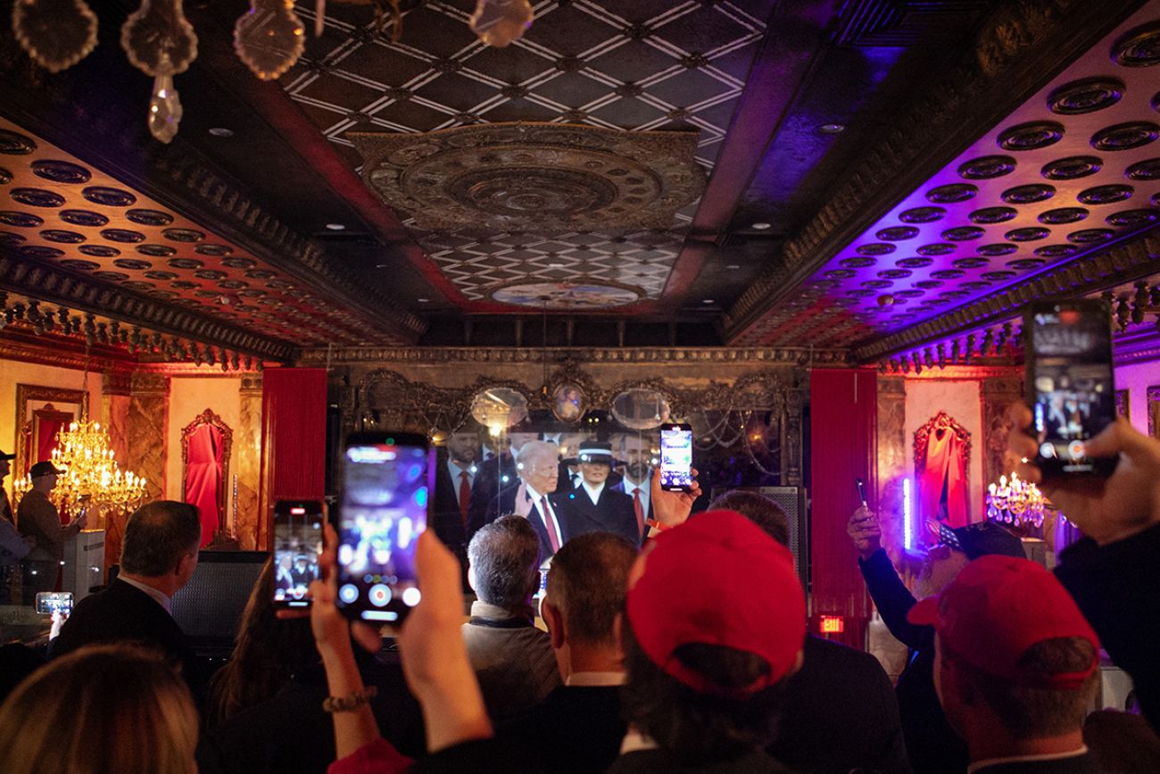 People inside a theater watching Donald Trump being sworn in