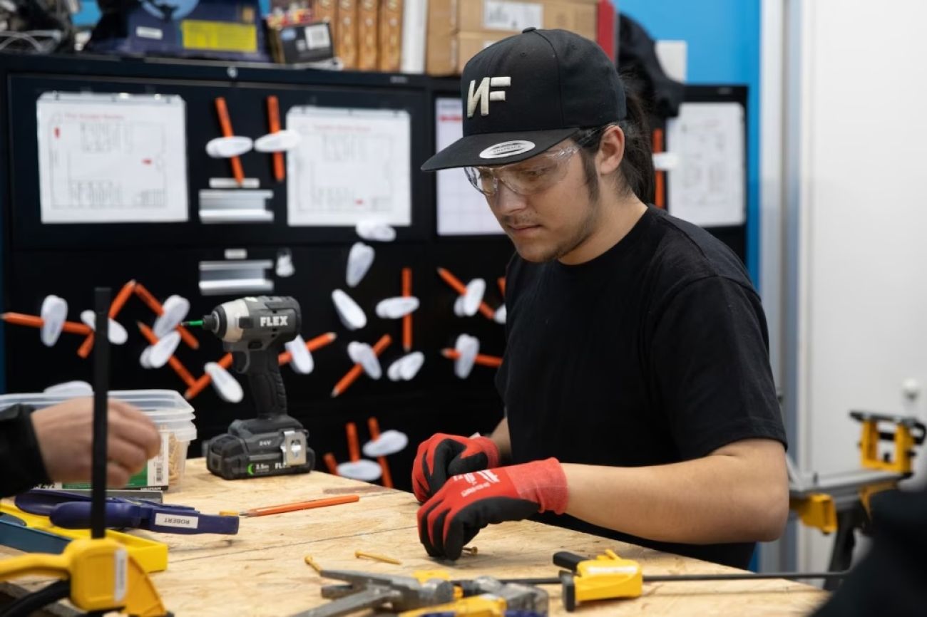 Lucian O’Donnell is at work bench with googles
