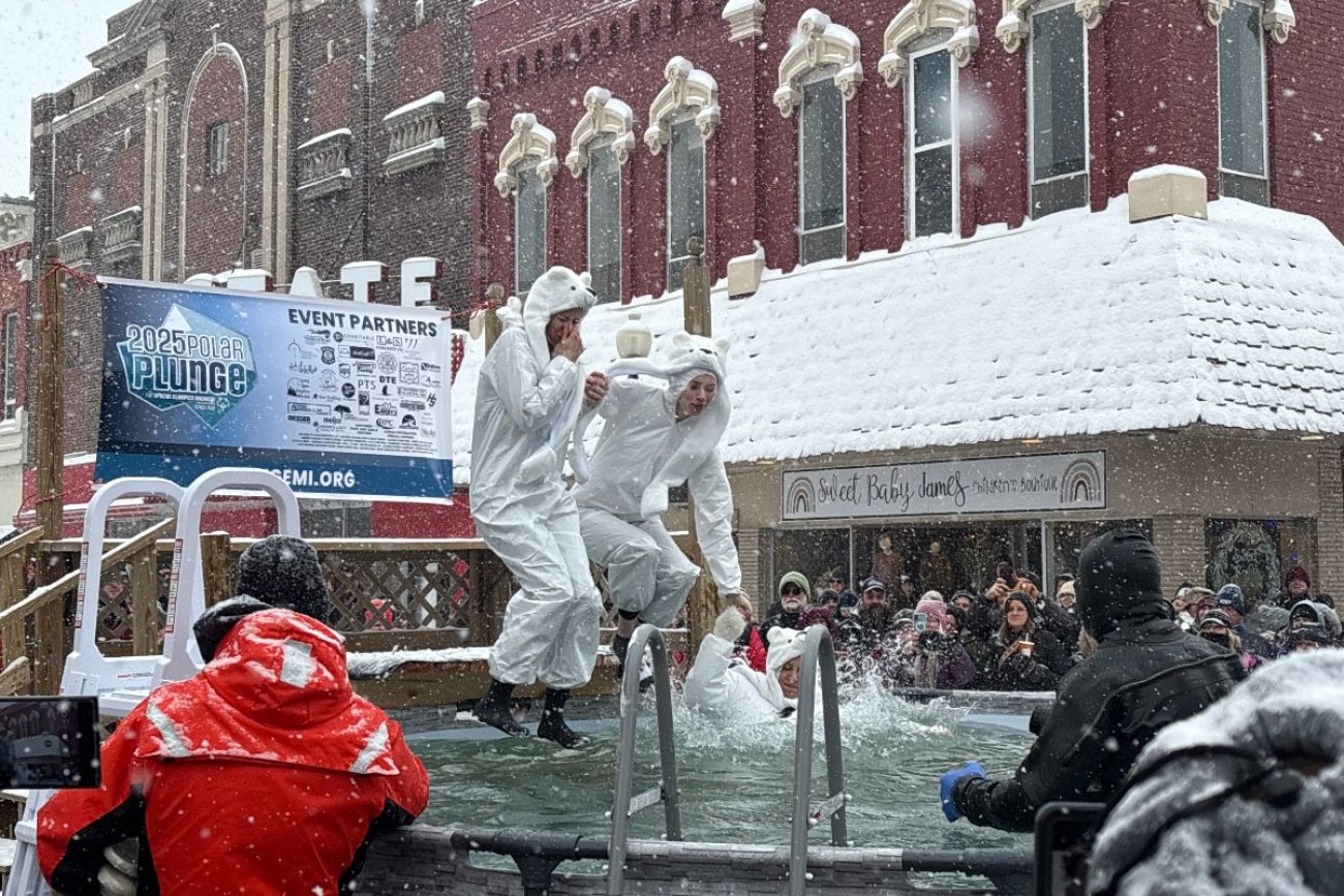 Three people jump in a pool in snowy Alpena, Michigan.