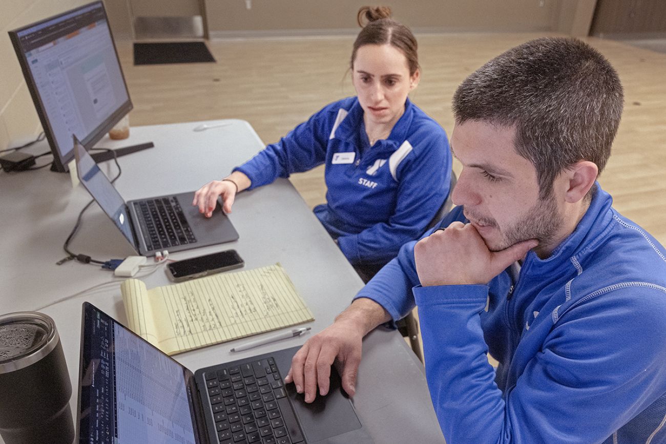 Two people looking at computers on a table.