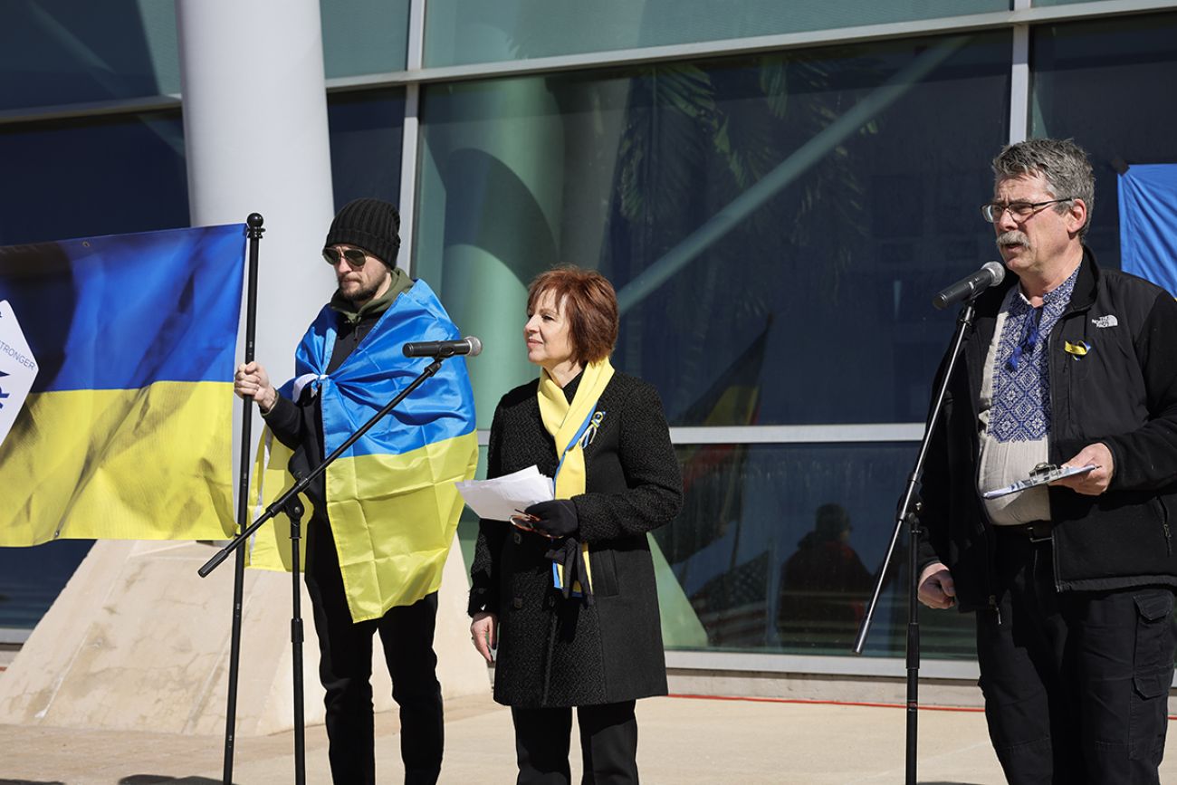 Andriy Pereklita speaking in a microphone. Two people stand next to him.
