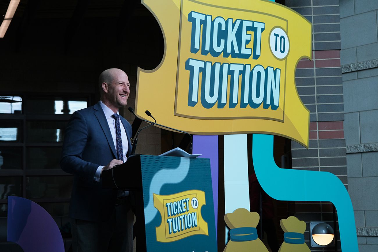 Lansing School District Superintendent Ben Shuldiner stands at a podium for the Ticket to Tuition competition in Michigan.