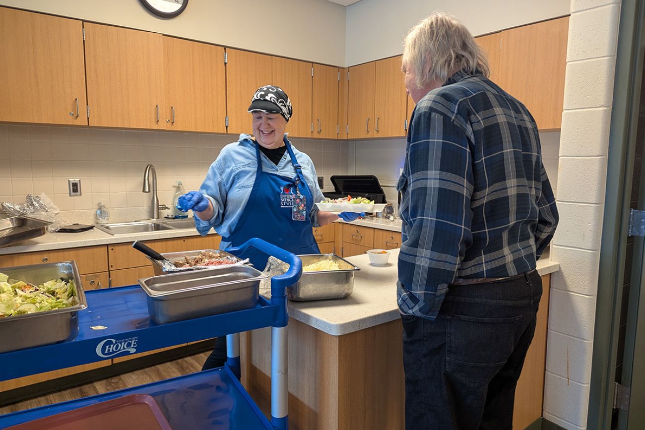 Diane DeCoster, a food service aide in Macomb County, serves an older gentleman soup.