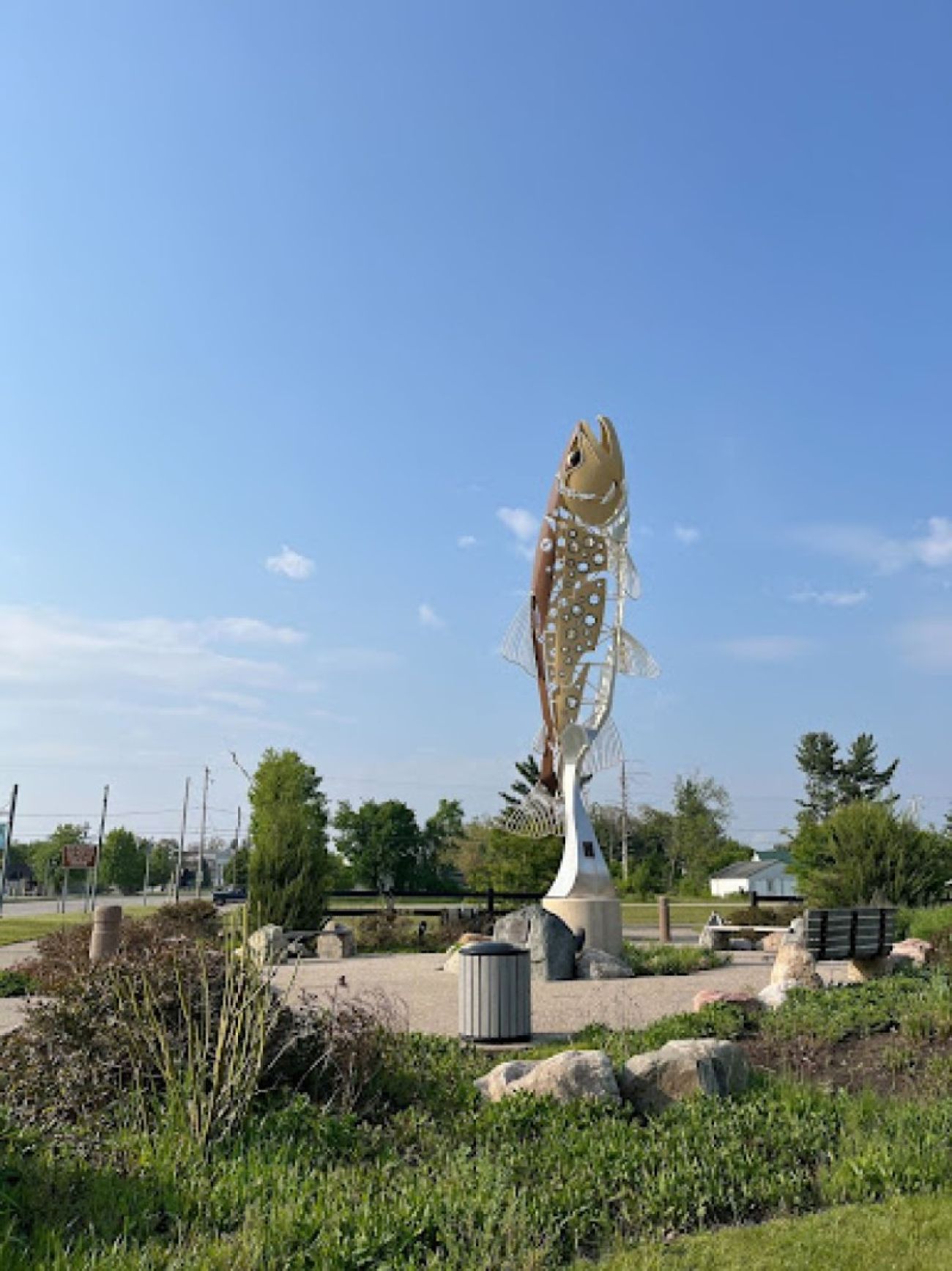 A sculpture of a brown trout sits in a grassy area in Baldwin