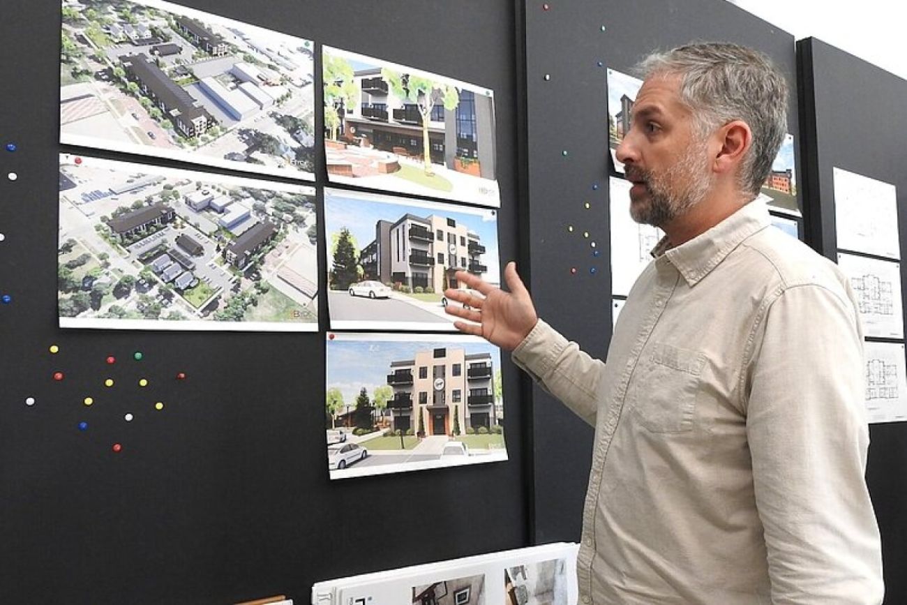 A man looks at building plans pinned up on a wall