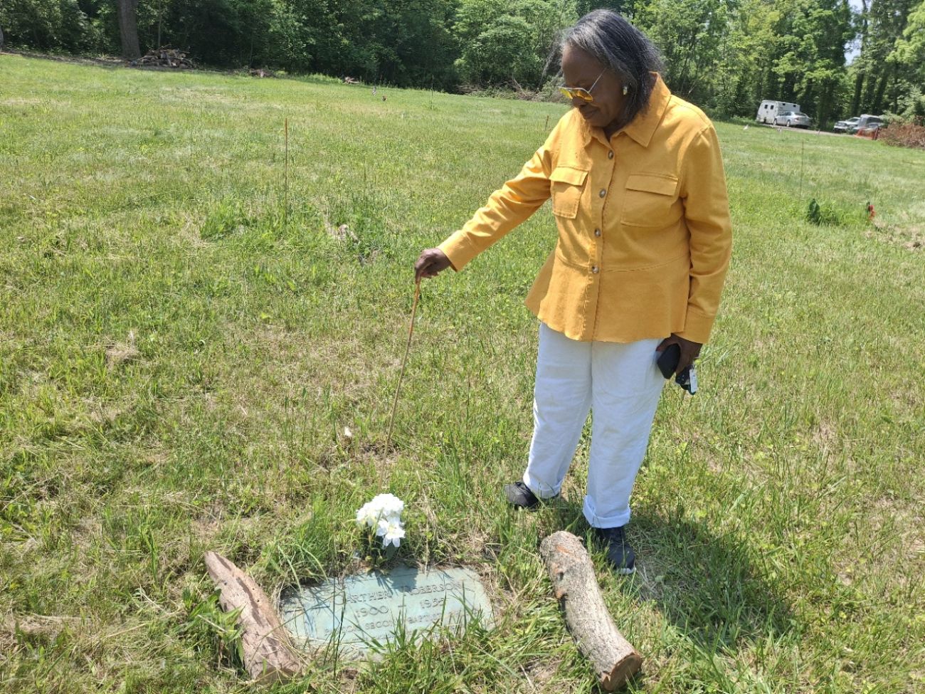 Mattie Odessa Smith, wearing a yellow jacket, is next to a gravestone.