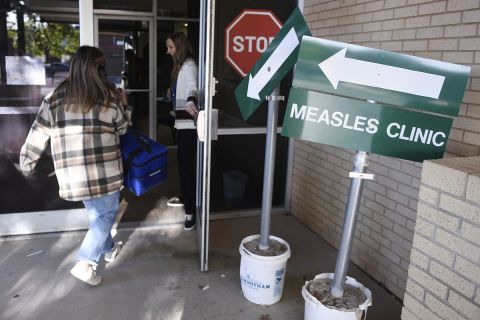 Someone walking into a health department. There's a green sign that says "Measles Clinic."