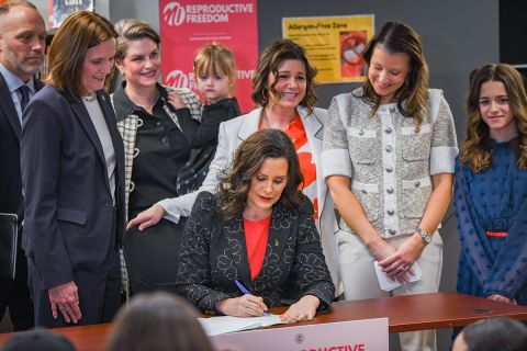 Gov. Gretchen Whitmer signing a bill. Lawmakers and the Myers family surround her.