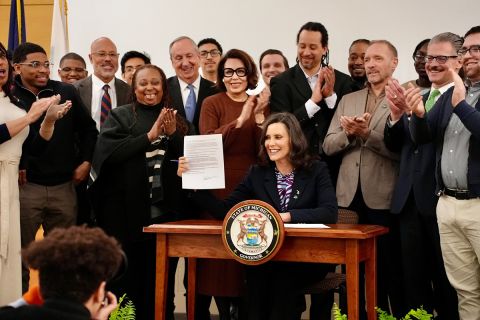 People clapping around Gov. Gretchen Whitmer. 