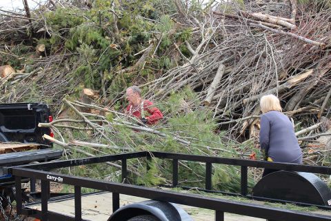 Terry and Nancy Chamberlin picks up trees. A trailer is nearby. 