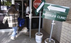 Someone walking into a health department. There's a green sign that says "Measles Clinic."