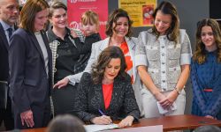 Gov. Gretchen Whitmer signing a bill. Lawmakers and the Myers family surround her.