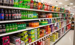 A view of the soda aisle of a grocery store, featuring several brands and colors of carbonated beverages.